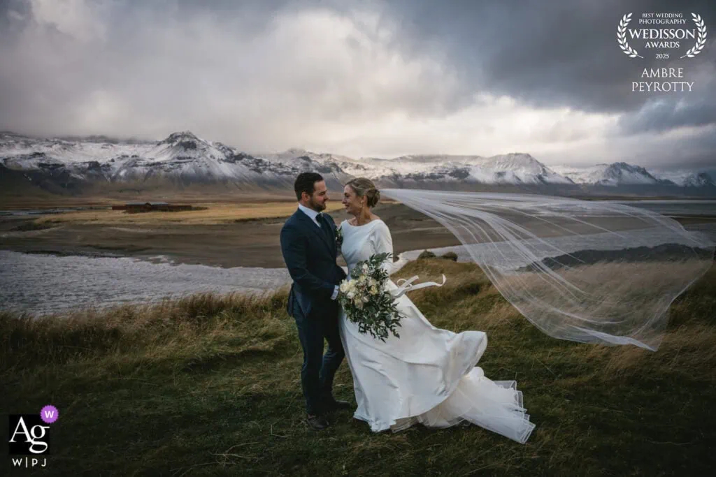 Bride and groom by an Iceland lake with snowy mountains, a popular destination for couples who want to elope