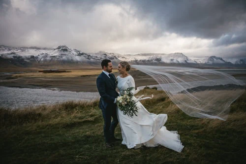 Couple standing in wild Icelandic landscapes, the bride’s veil dancing in the wind like a spell