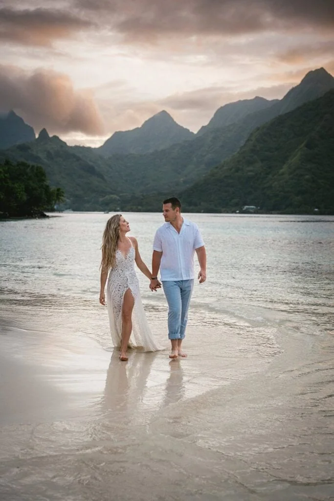 Elopement couple walking hand in hand on a tropical beach in Bora Bora at sunset.