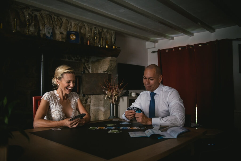 Braide and groom laughing as they play cards on their elopement in Central France