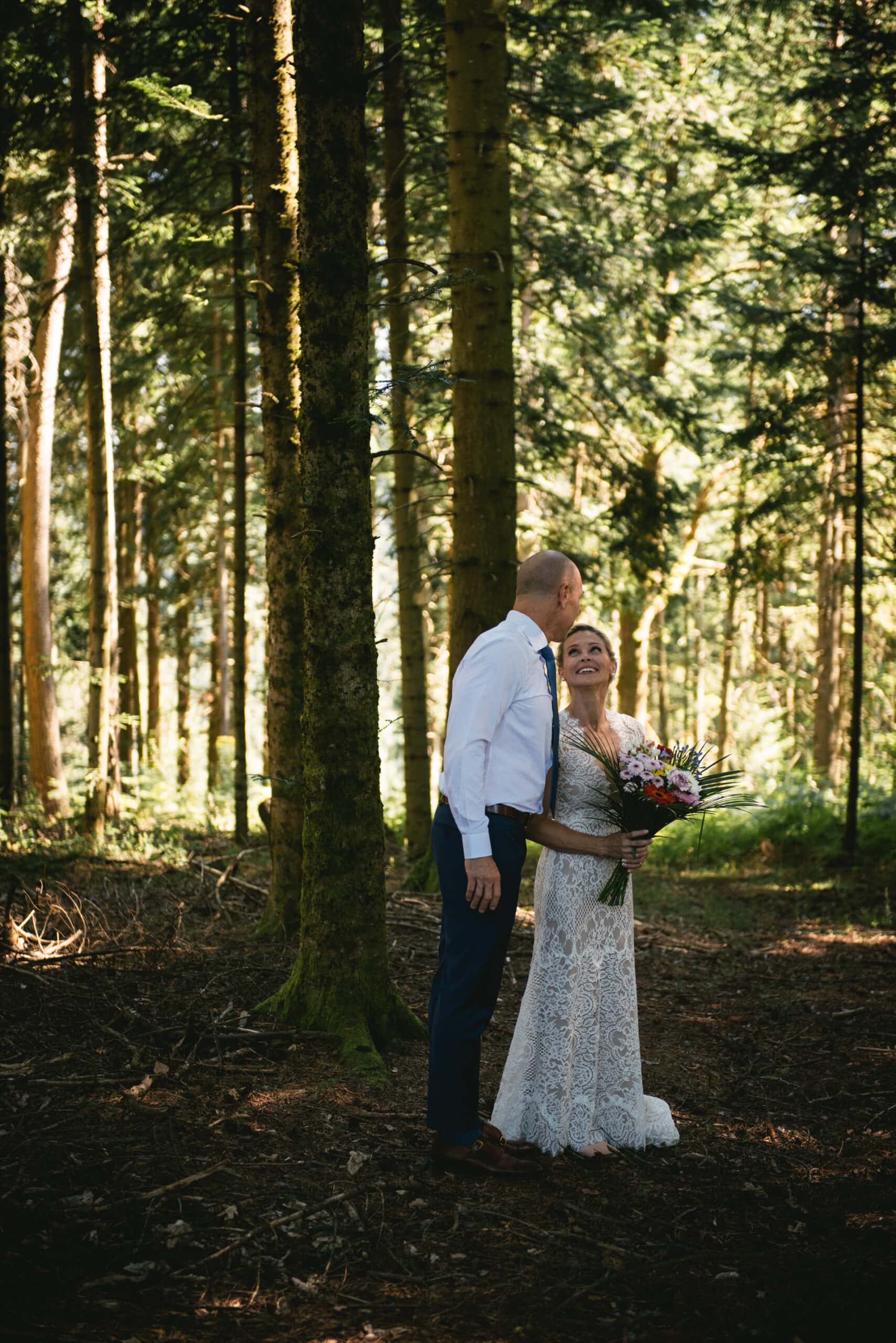 Bride holding a bouquet with her groom in a forest on their elopement in Central France