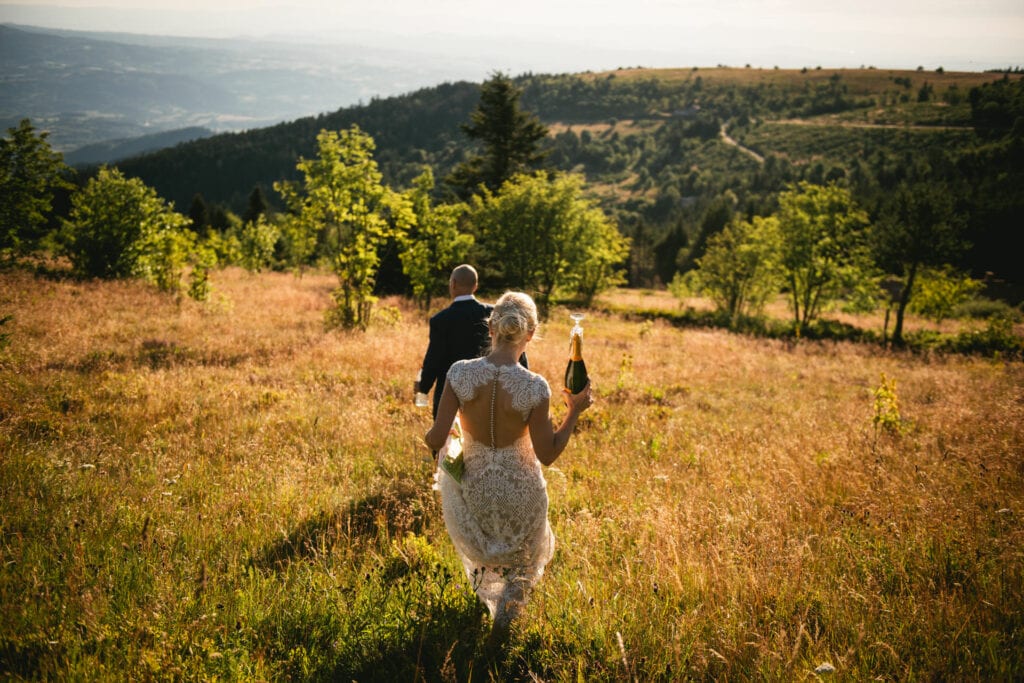 Bride and groom walking down a field overlooking the Auvergne region for a picnic after their elopement in Central France