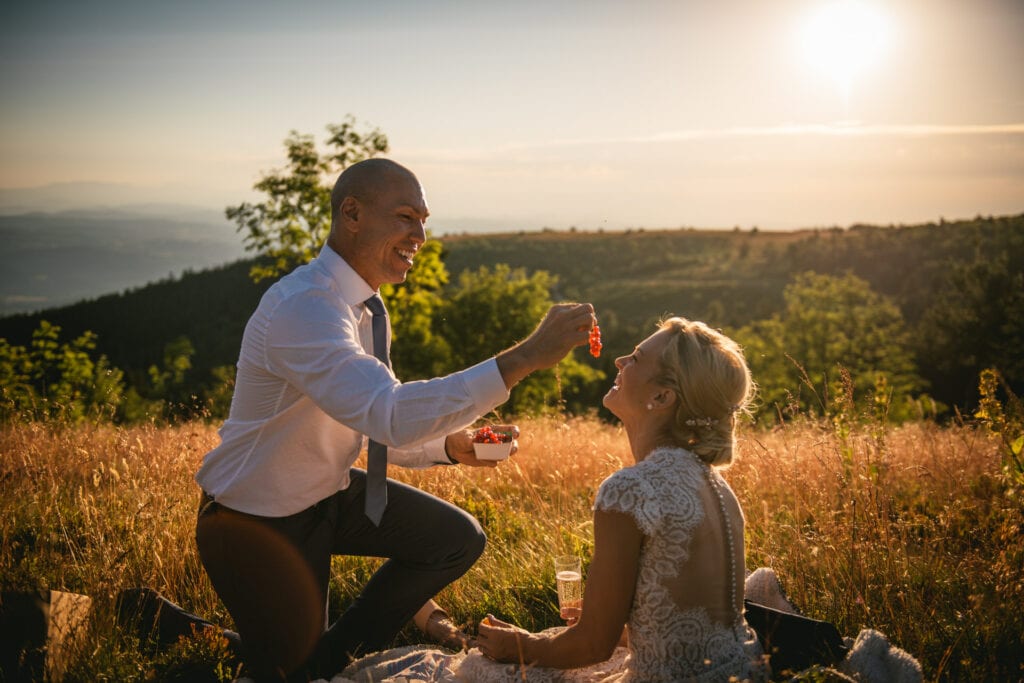 Groom offering some gooseberries to his bride during their sunset picnic after their elopement in Central France