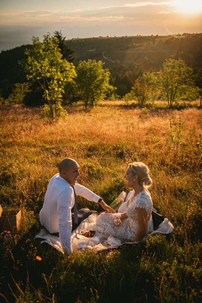 Bride and groom enjoying their sunset picnic with a view on the nearby mountains after their elopement in Central France
