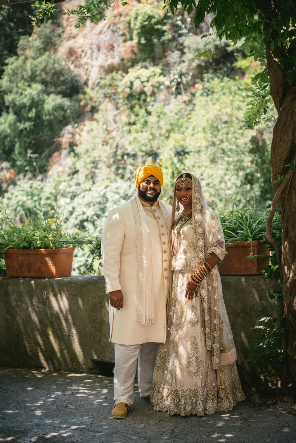 Couple in their traditional Sikh wedding outfits posing in front of flowers during their elopement on the Amalfi Coast