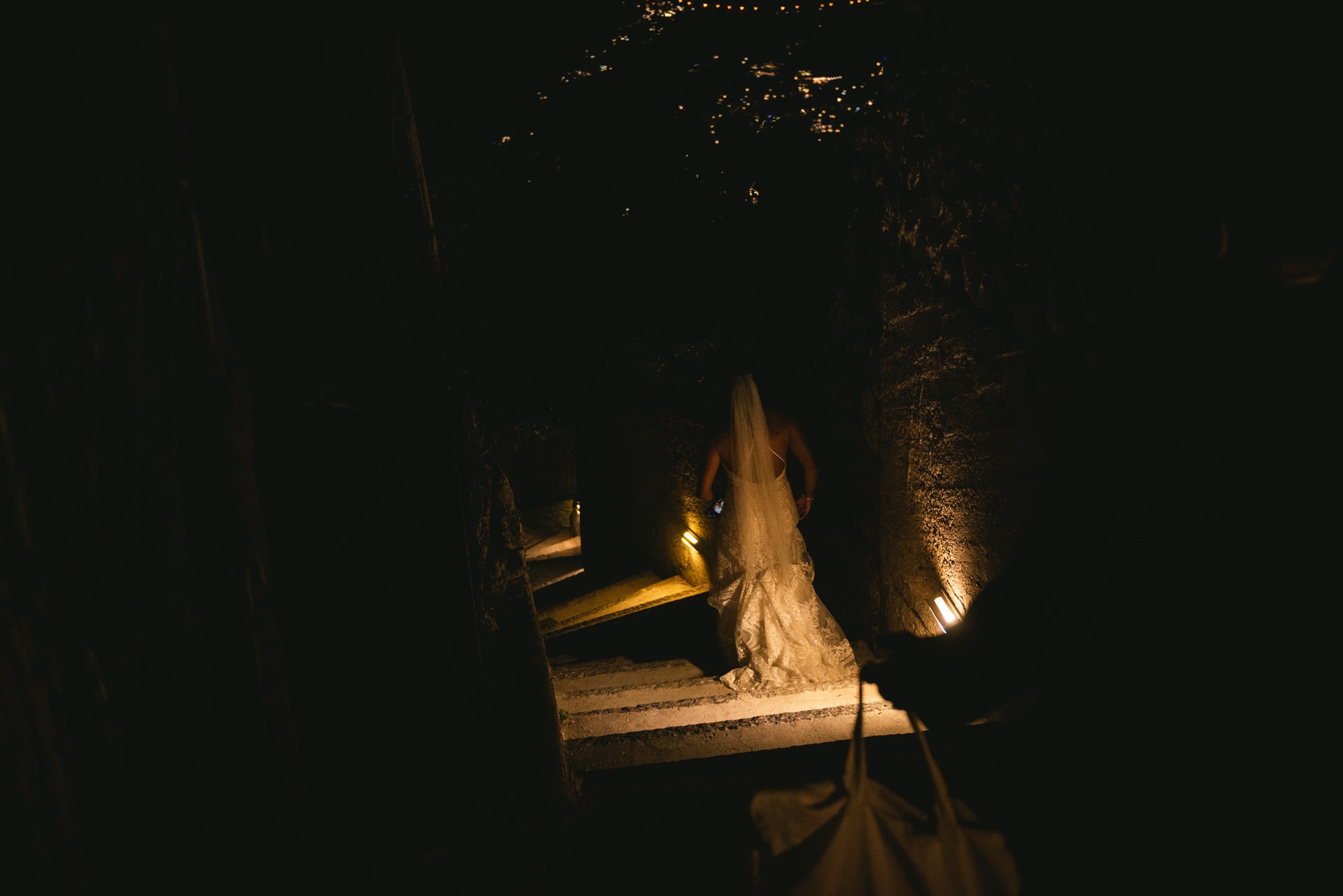 Atmospheric shot of a bride walking down some stairs at night in Positano