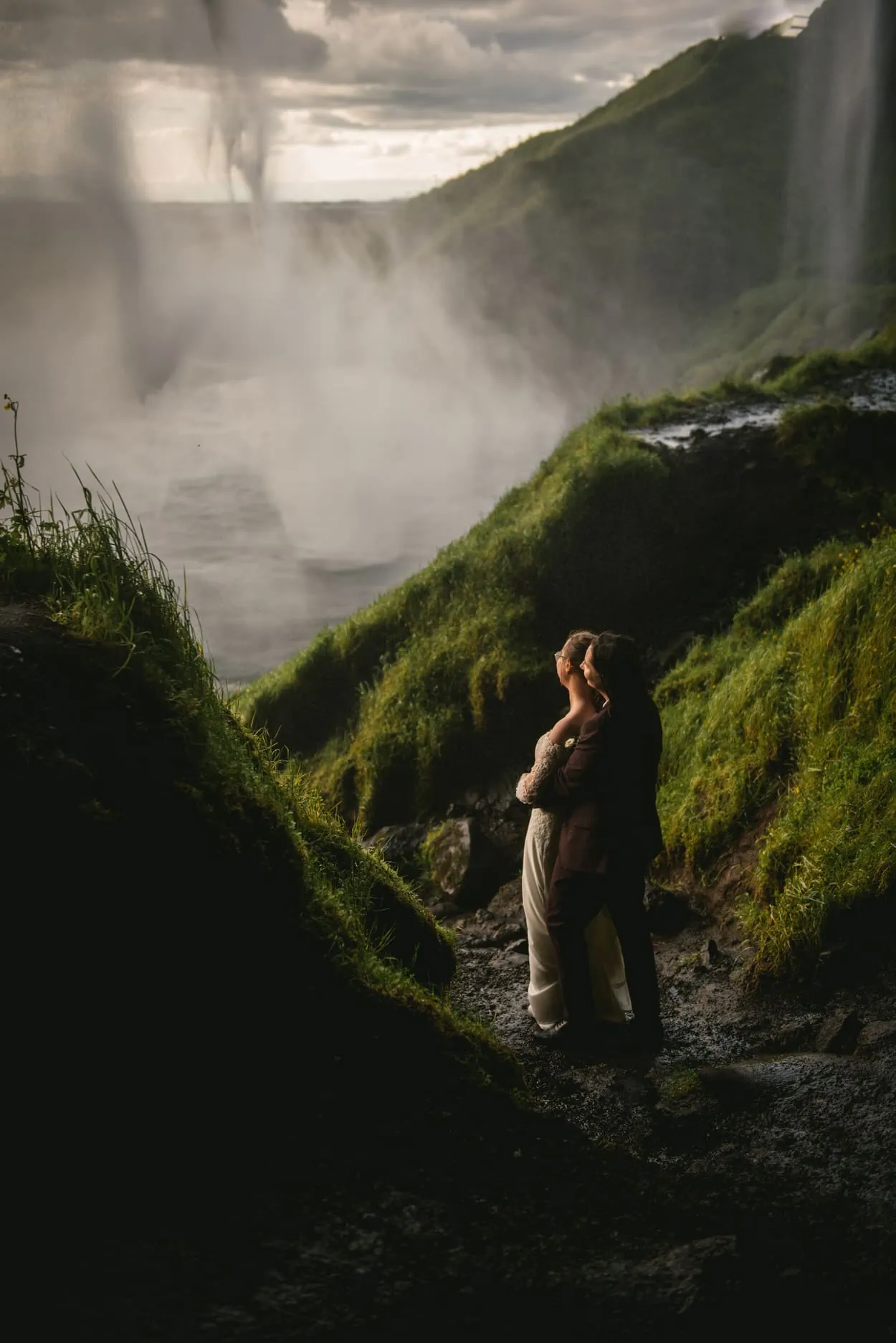 Same-sex couple posing in front of Seljalandsfoss during their elopement ceremony in Iceland