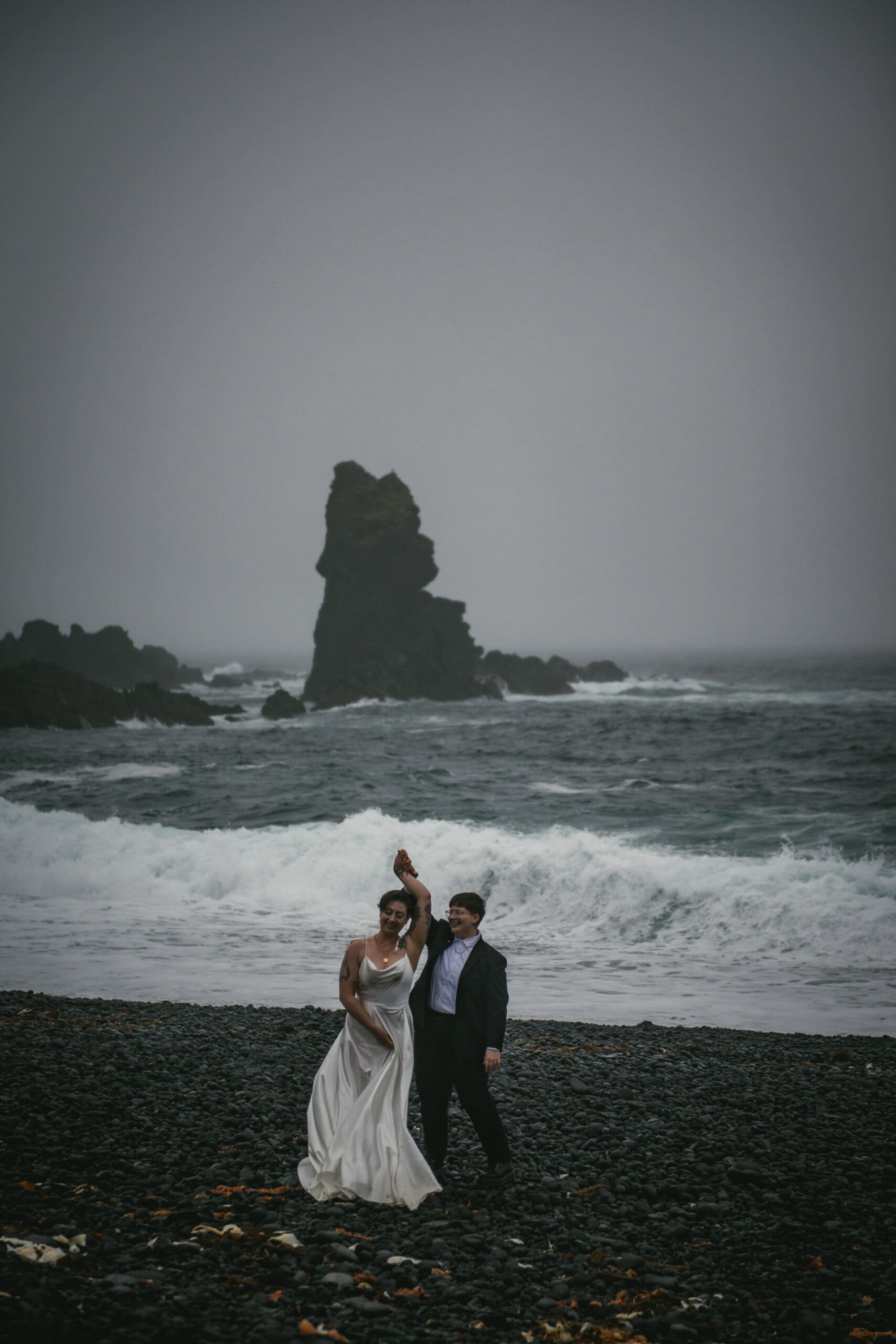 Couple dancing on a black sand beach on their elopement day