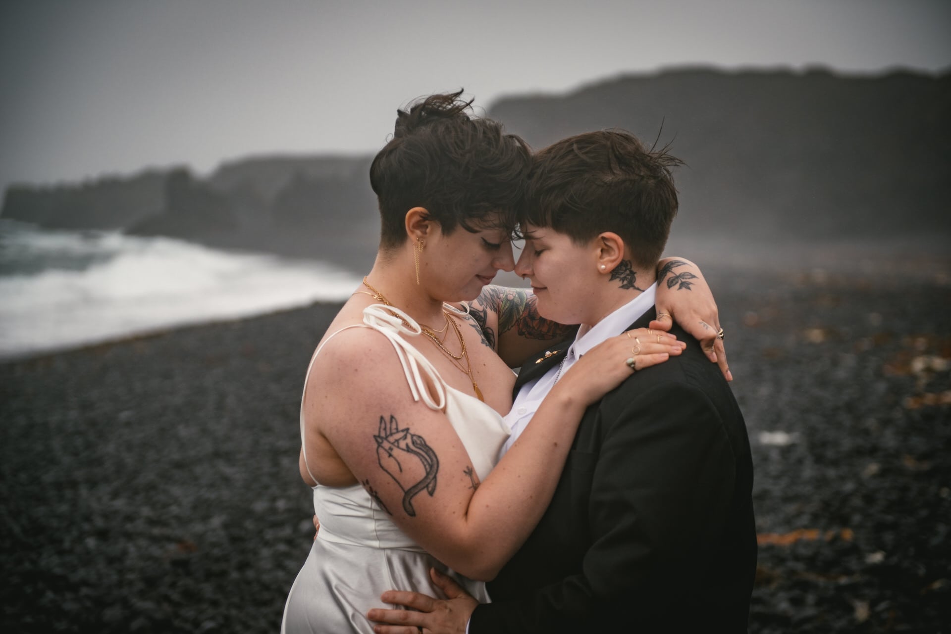 Couple facing each other on an icelandic black sand beach on their elopement day