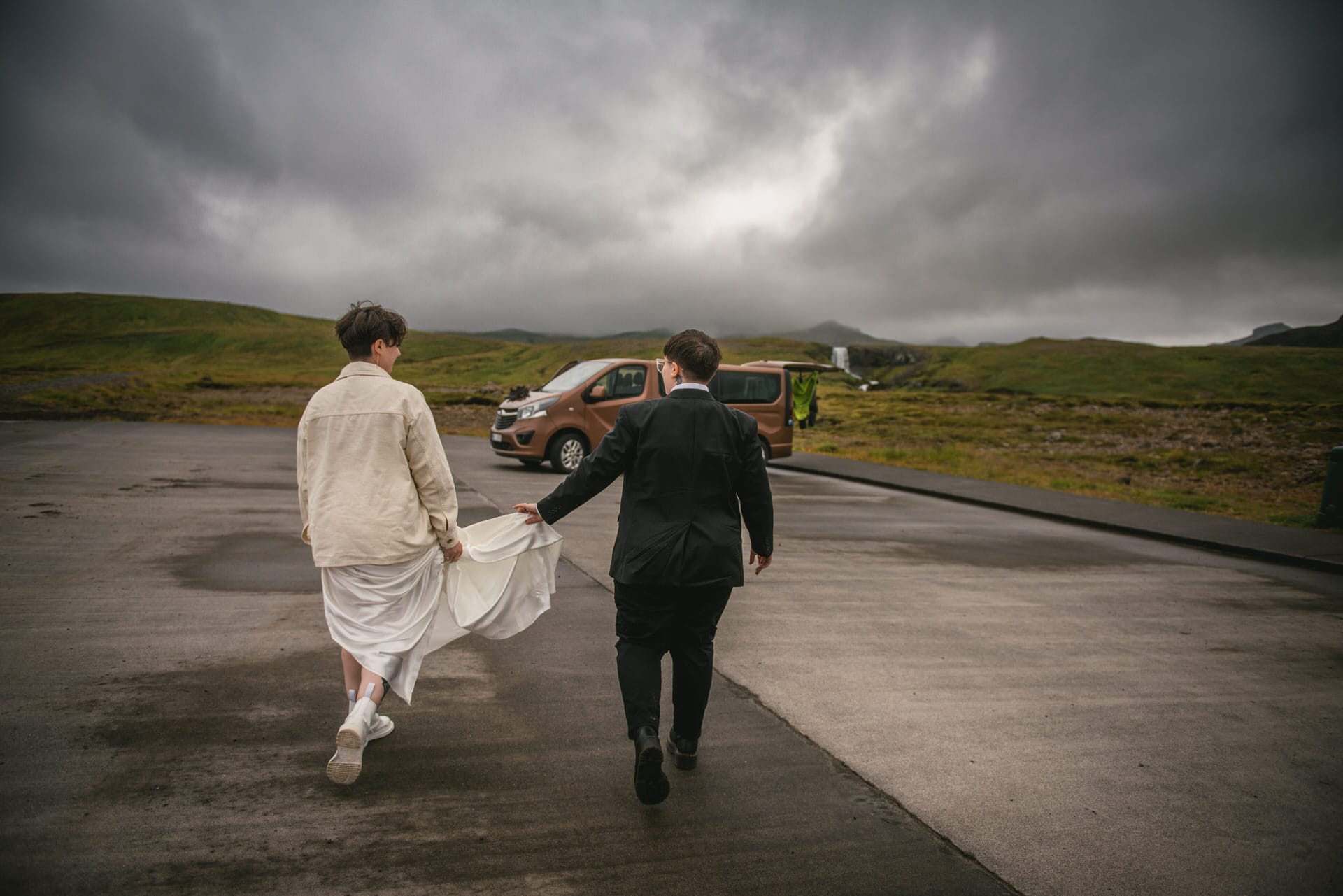 Same-sex couple walking towards a waterfall on their elopement day in Iceland