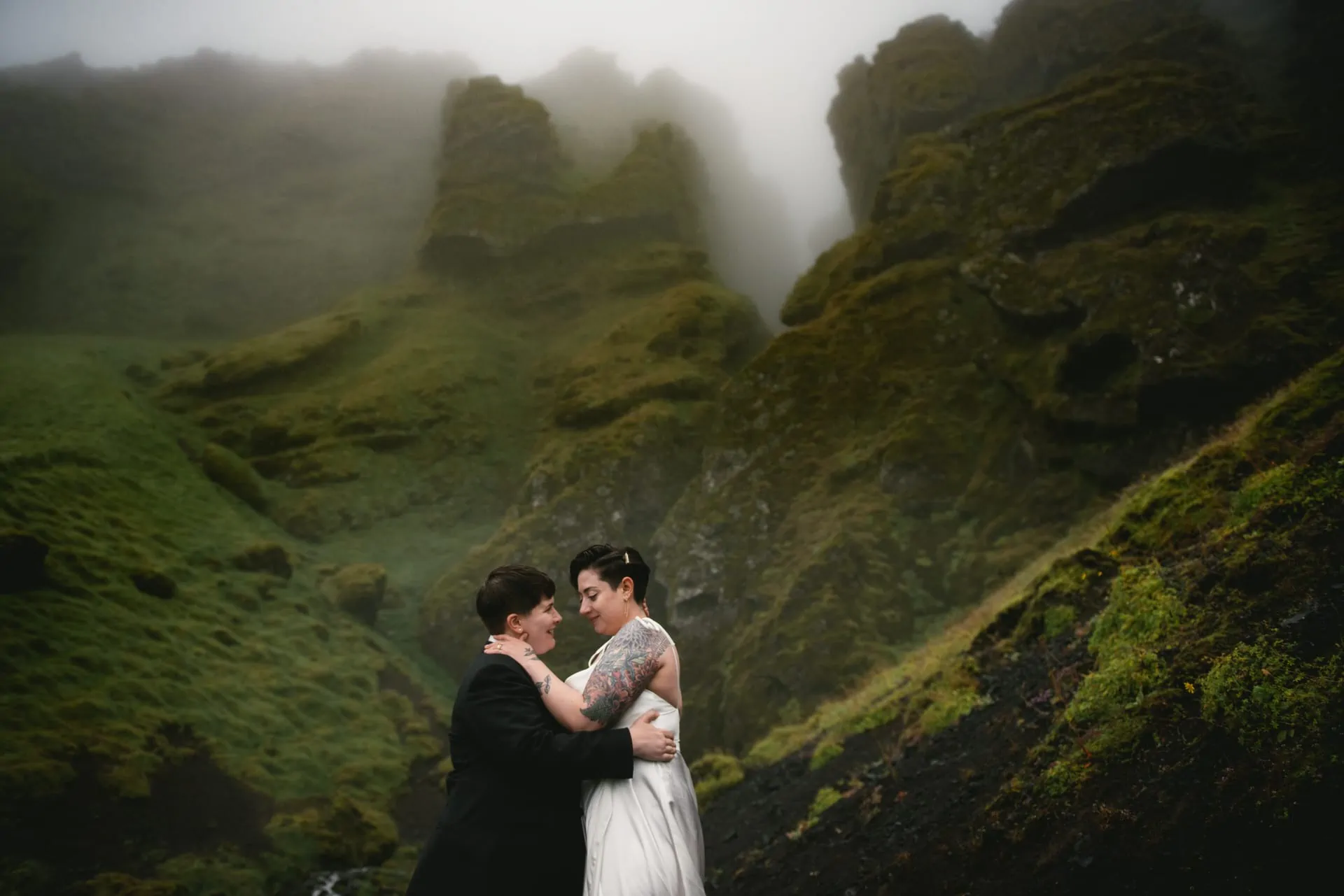 Same-sex couple posing in front of the Raudhfeldsgja gorge on their elopement day in Iceland