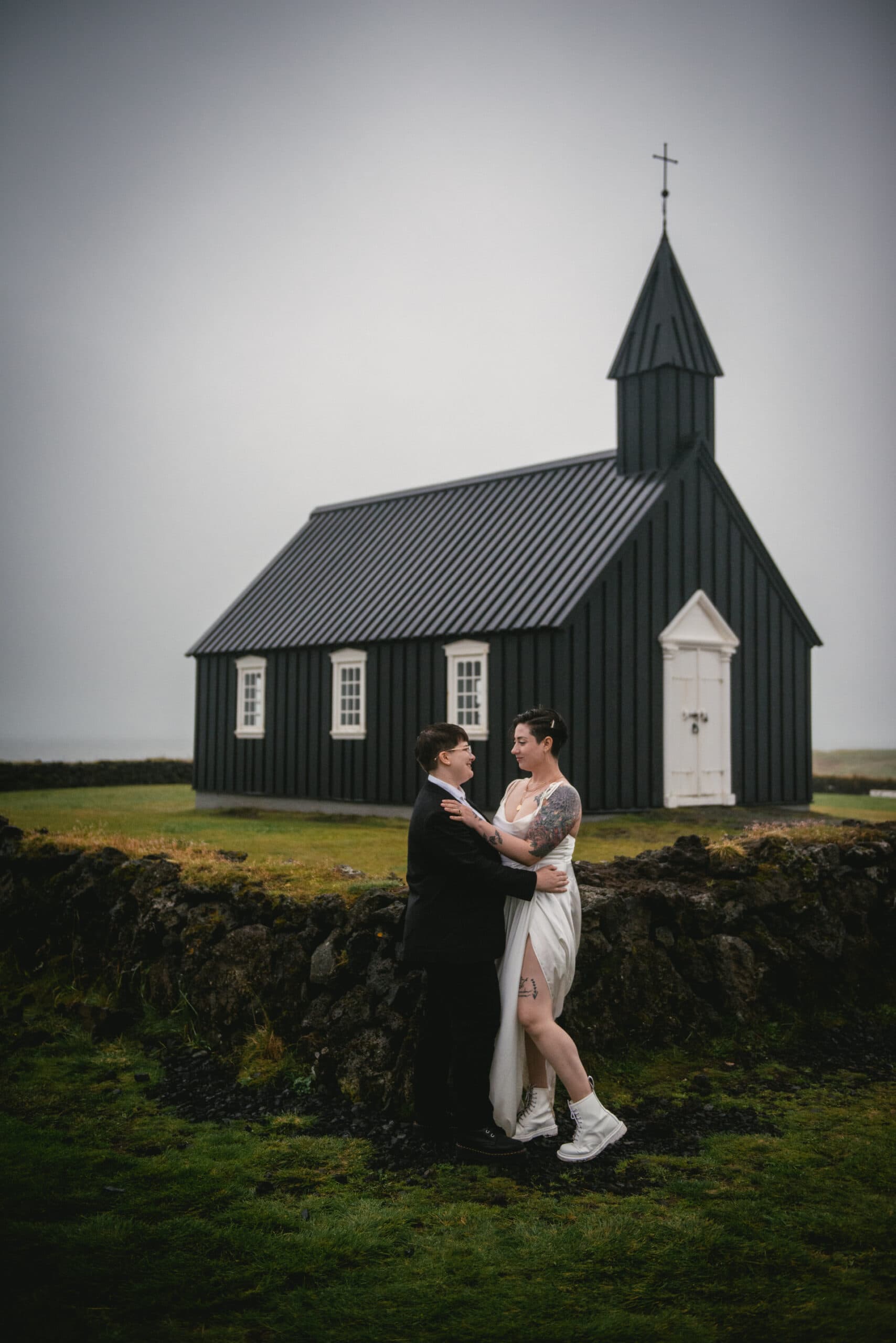 Same-sex couple posing in front of the Budhir church on their elopement day in Iceland
