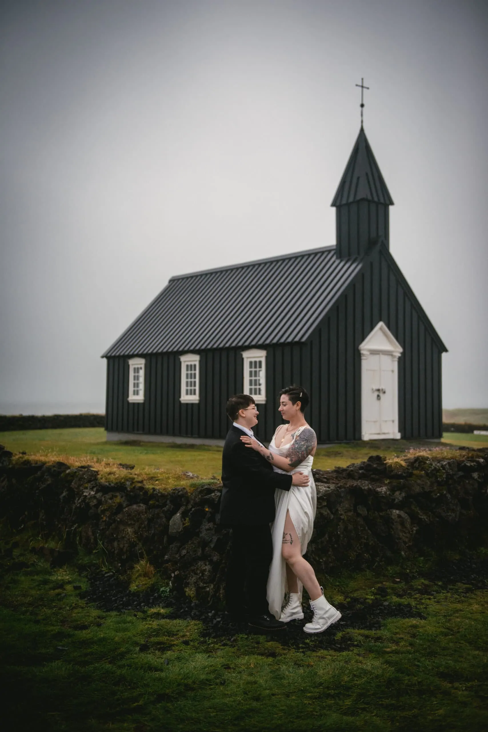 Same-sex couple posing in front of the Budhir church on their elopement day in Iceland
