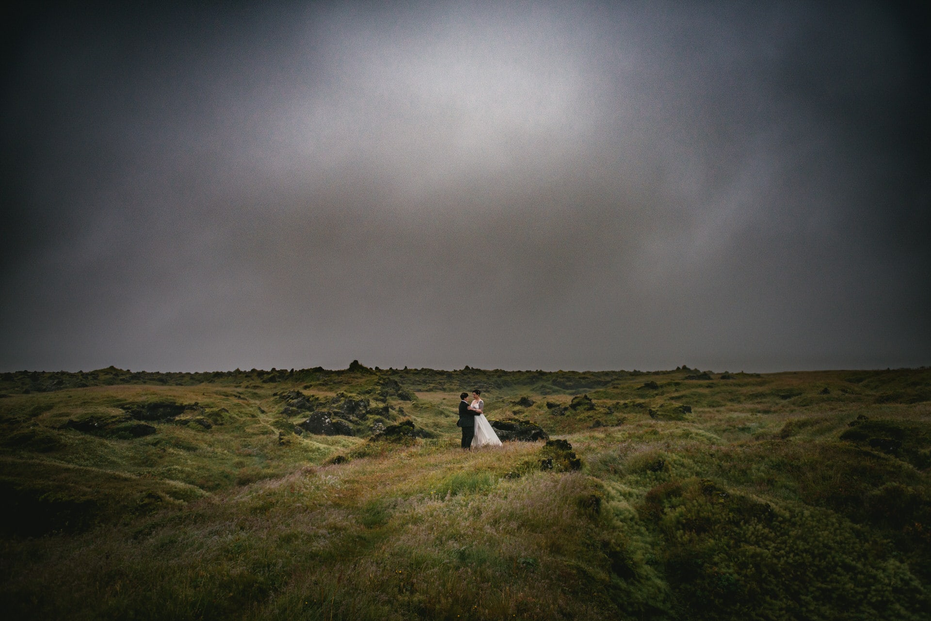 Same-sex couple posing in a lava field on their elopement day in Iceland