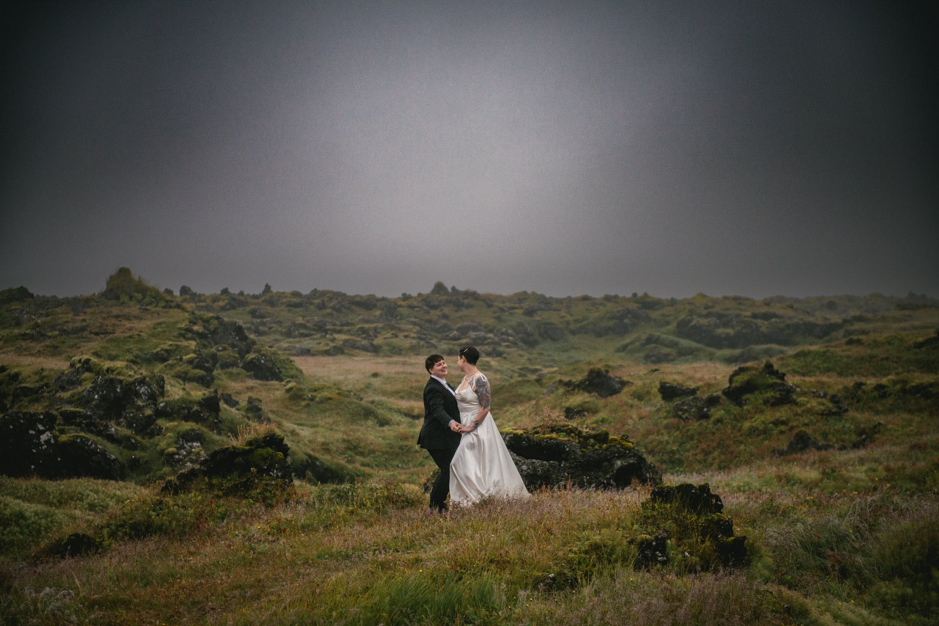 Same-sex couple posing in a lava field on their elopement day in Iceland