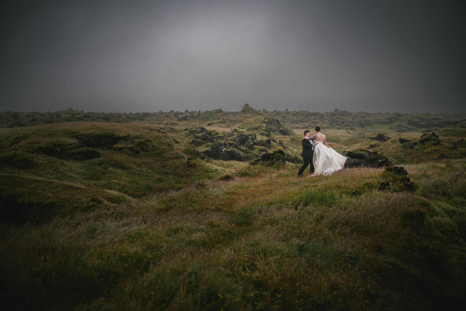 Same-sex couple dancing in a lava field on their elopement day in Iceland