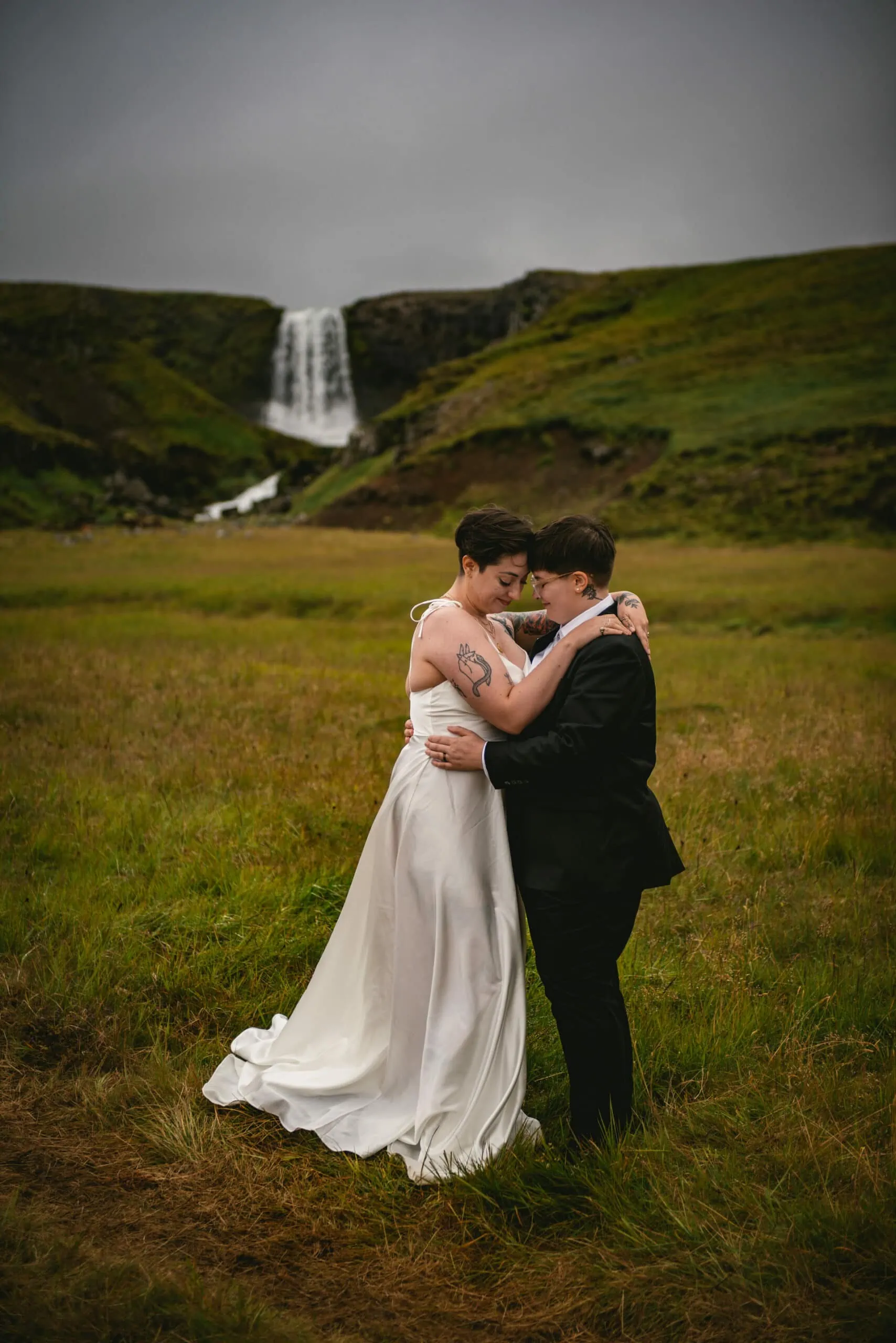 Same-sex couple hugging in front of Grundarfoss
