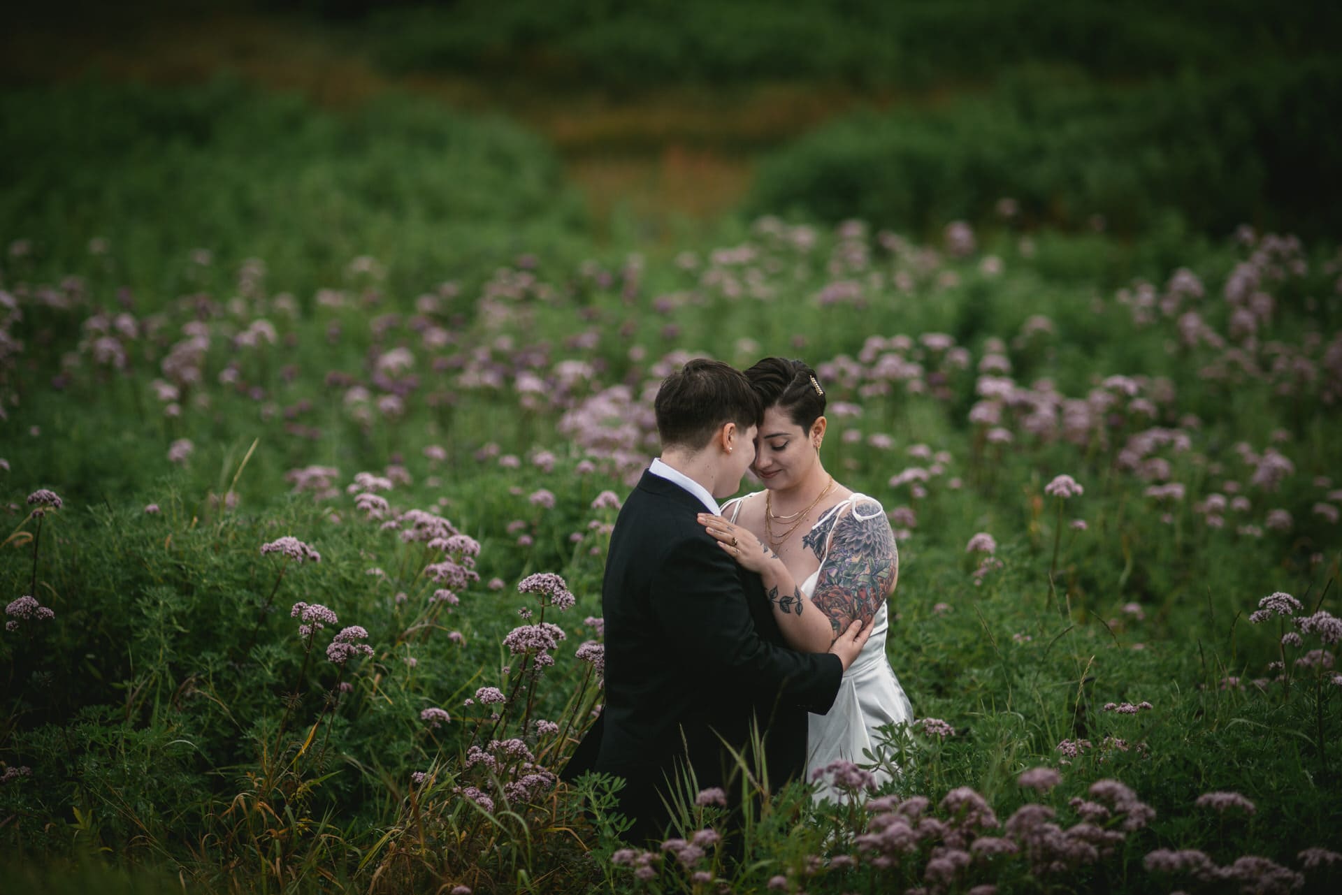 Same-sex couple posing in  a field of flowers on a rainy day, on their elopement day in Iceland