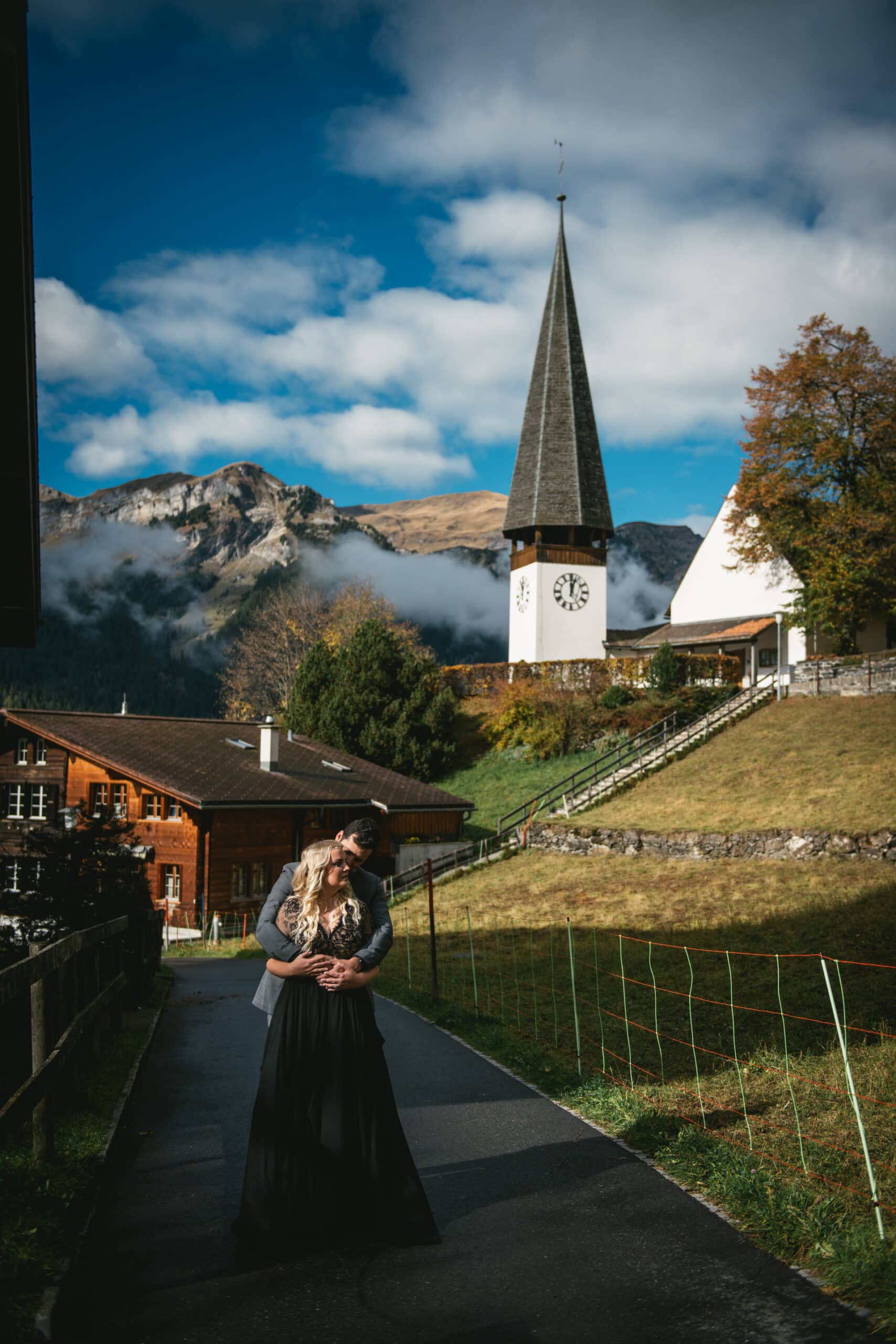 Couple hugging on their elopement day with the Wengen church in the background