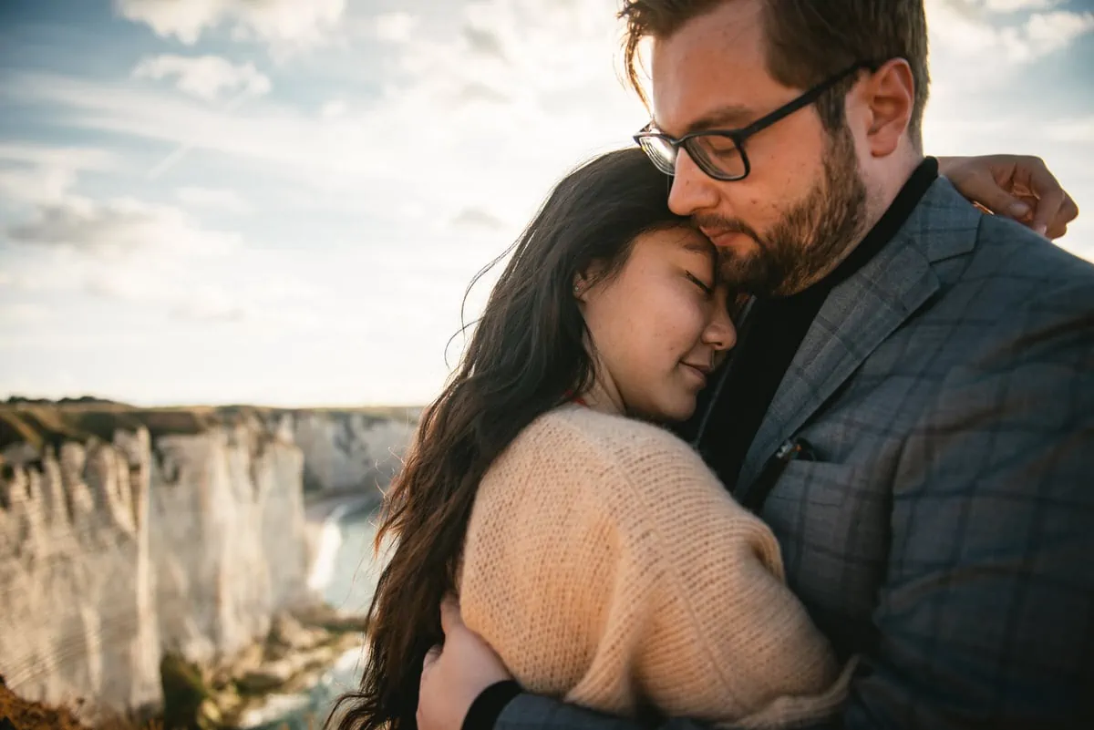 Couple hugging with the Etretat cliffs in the background before their elopement in Normandy