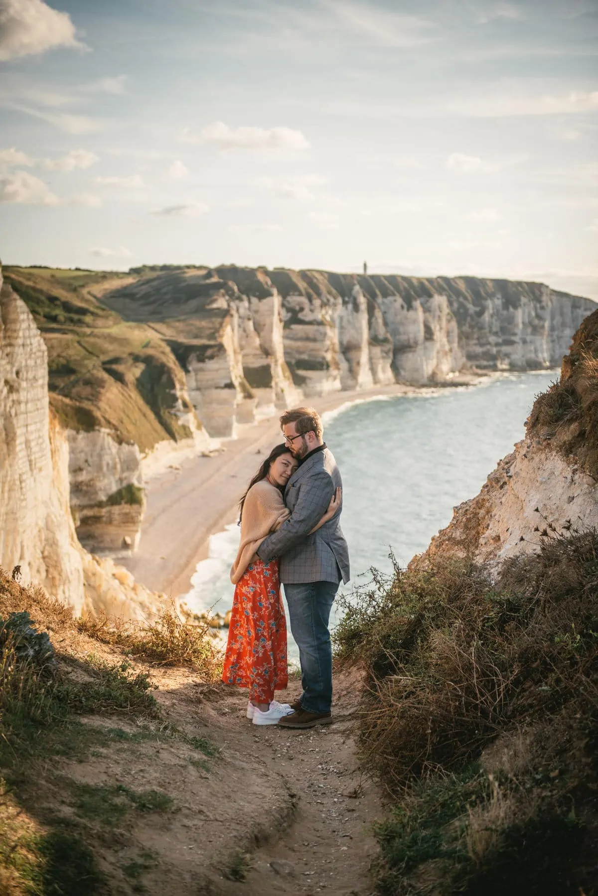 Couple hugging with the Etretat cliffs in the background before their elopement in Normandy
