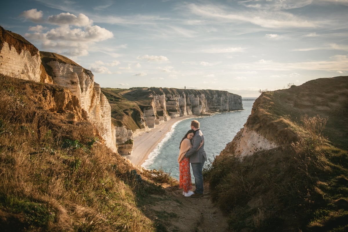 Couple hugging with the Etretat cliffs in the background before their elopement in Normandy