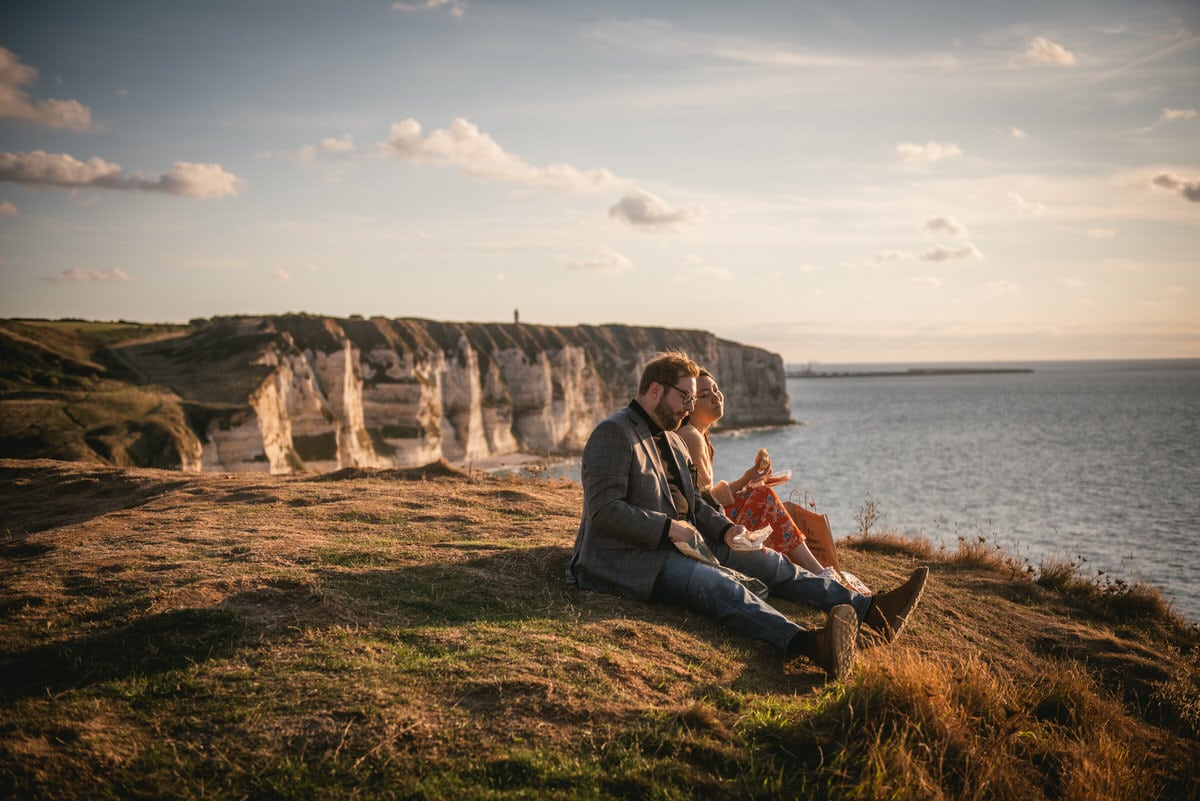 Couple eating Couple hugging with the Etretat cliffs in the background before their elopement in Normandy