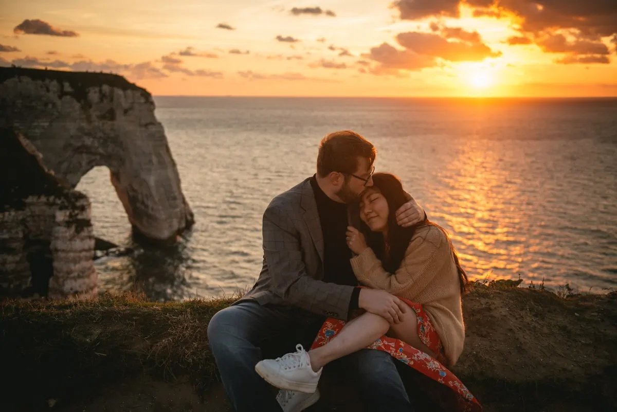 Couple hugging on top of the Etretat cliffs Couple hugging with the Etretat cliffs in the background before their elopement in Normandy