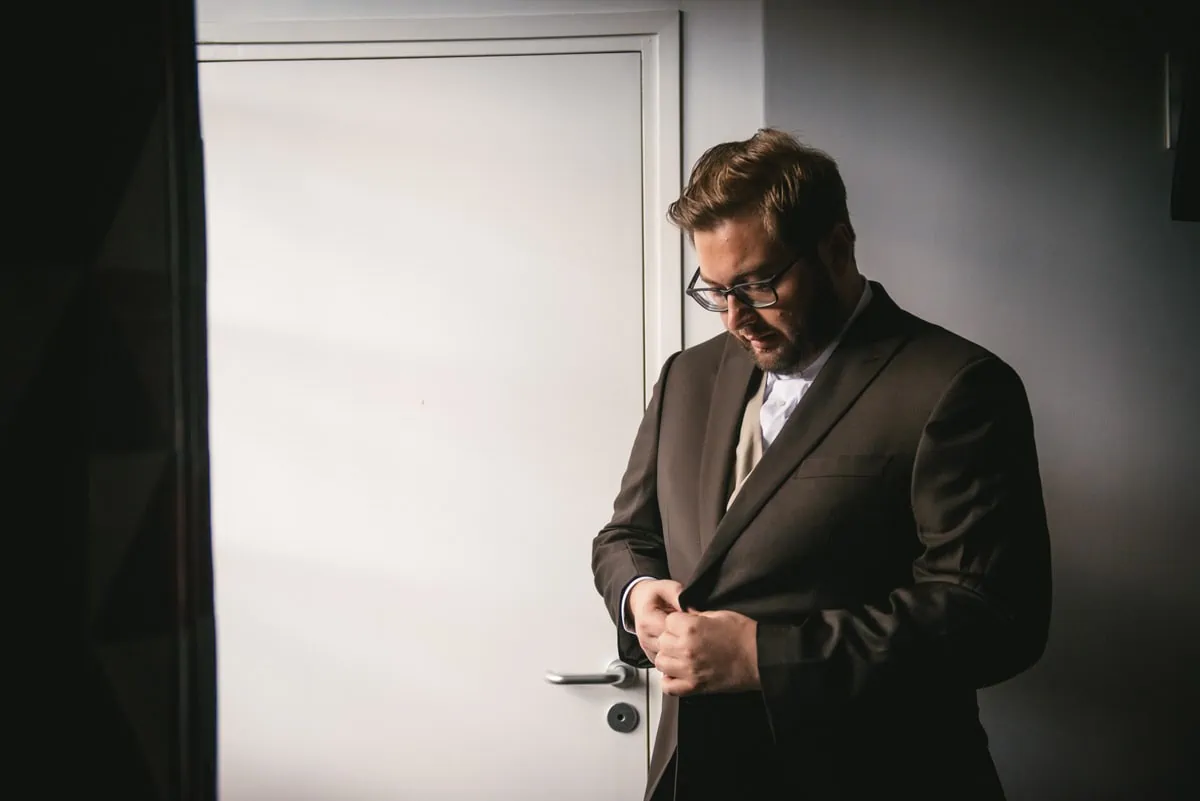 Groom putting his suit on before their elopement in Normandy