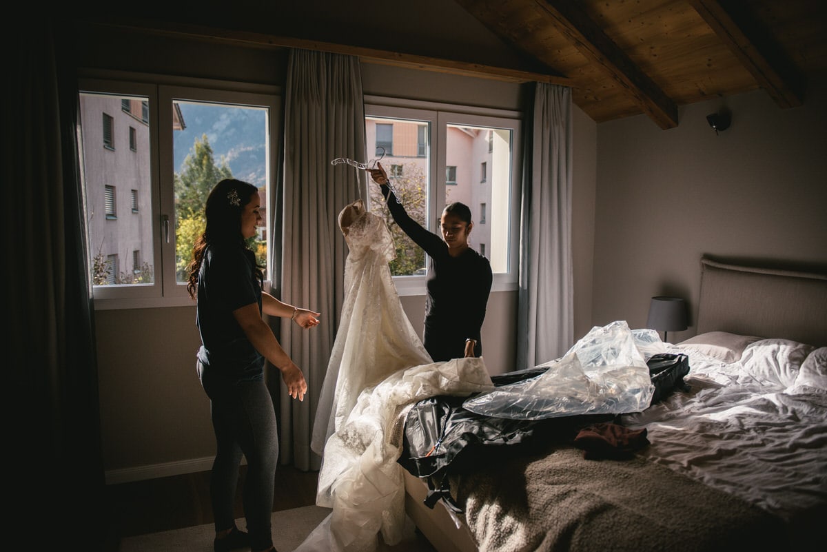 Couple on their elopement day in the Interlaken region of Switzerland - bride putting her dress on