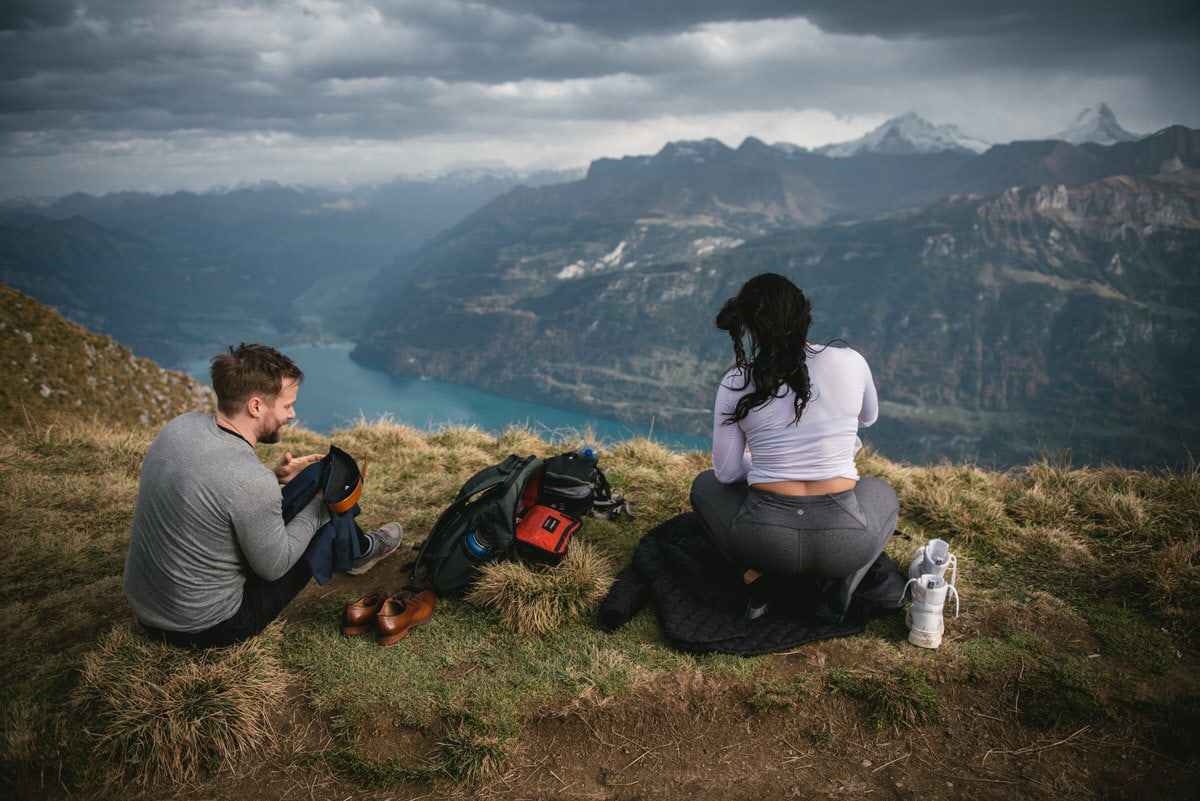 Couple on their elopement day in the Interlaken region of Switzerland - couple putting their wedding clothes on top of a mountain