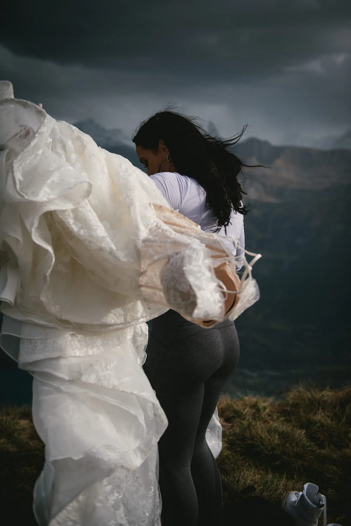 Couple on their elopement day in the Interlaken region of Switzerland - couple putting their wedding clothes on top of a mountain