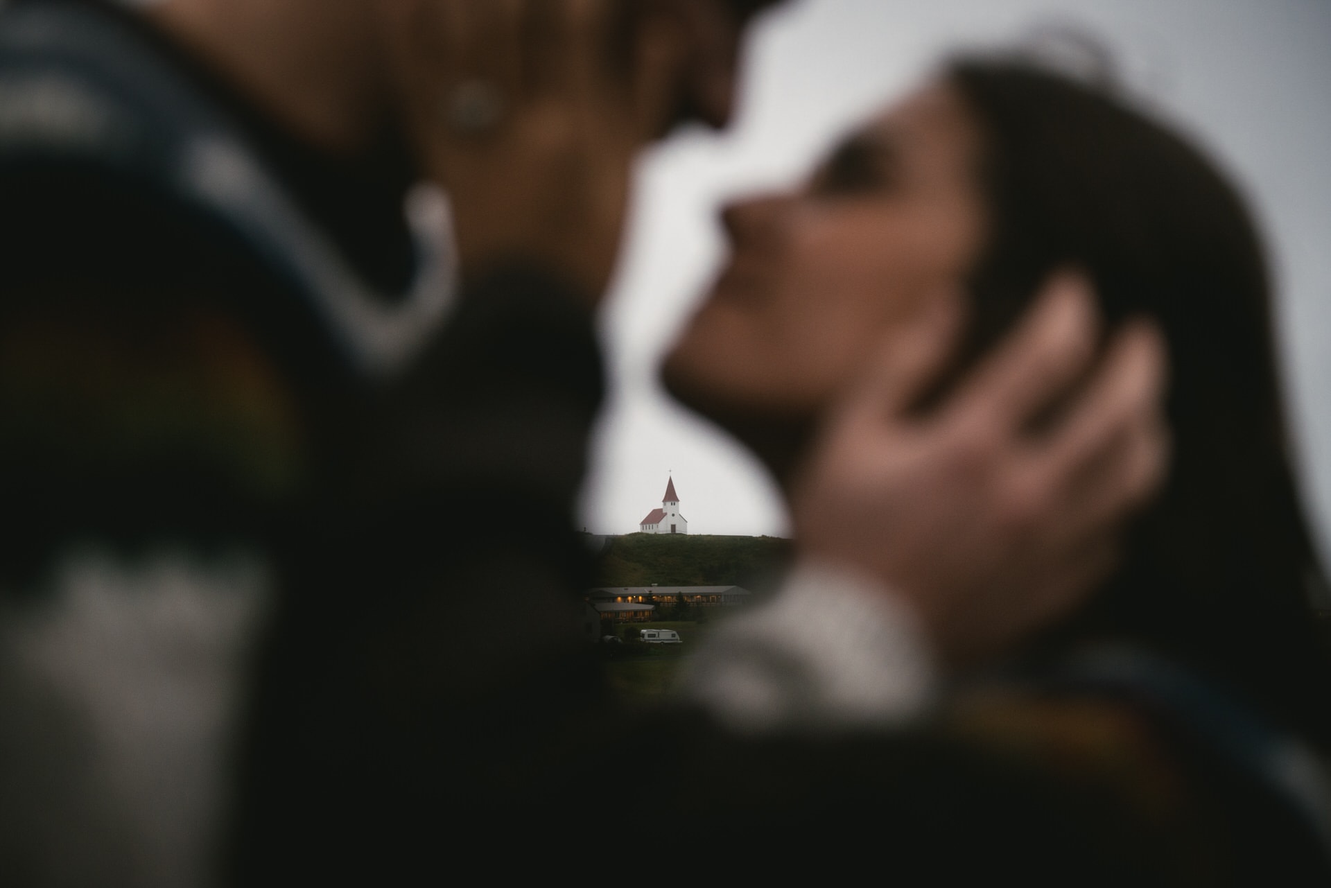 Couple kissing with the Vik church before their elopement in Iceland