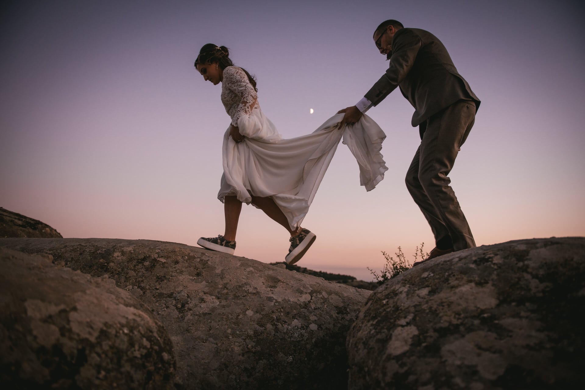 Couple walking on a rock with the moon on their Meteora wedding elopement