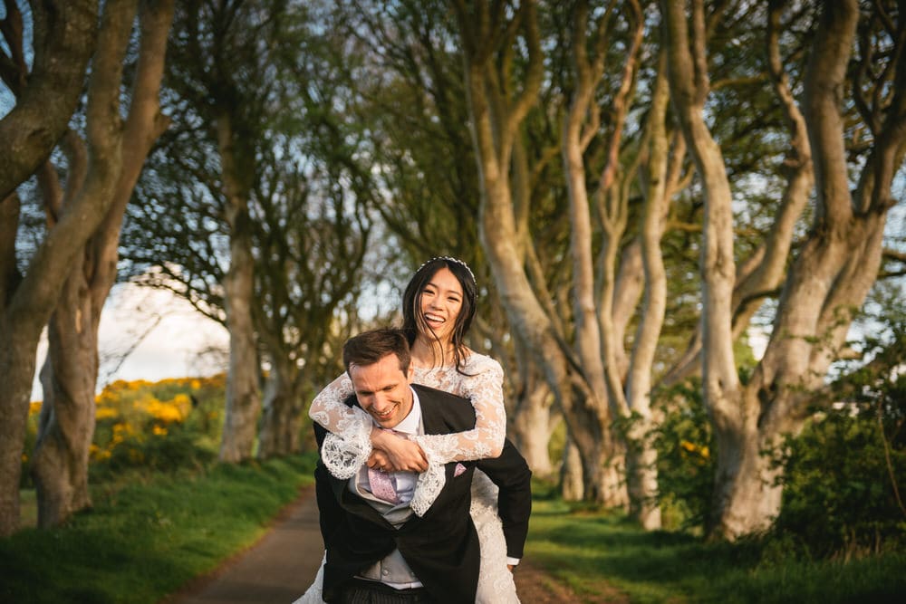 A candid moment of the couple laughing together under a canopy of trees during their Northern Ireland elopement.