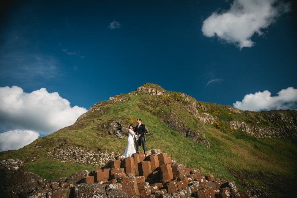 The couple standing on a cliff, with the vast sea stretching out before them during their Northern Ireland elopement.