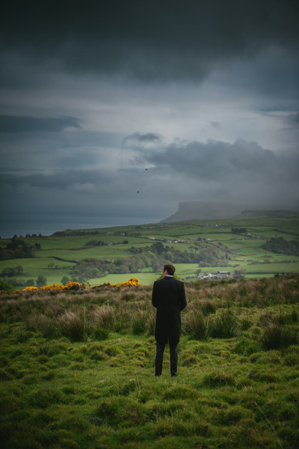 The groom standing on rolling green hills during his elopement in Northern Ireland