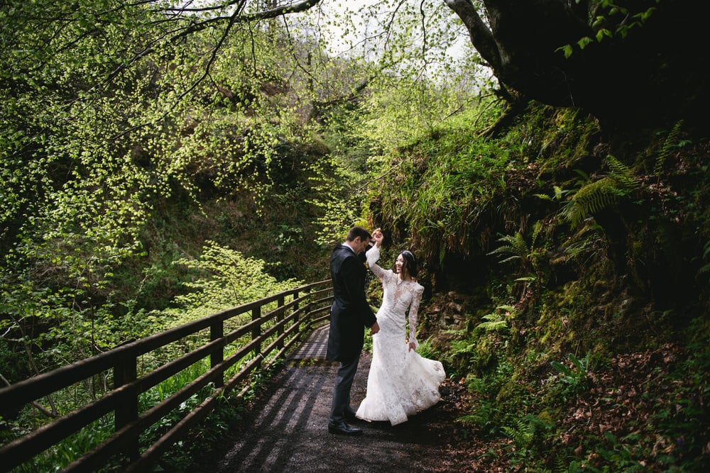 Quaint wooden bridge over a babbling brook in the forest during their Northern Ireland elopement.