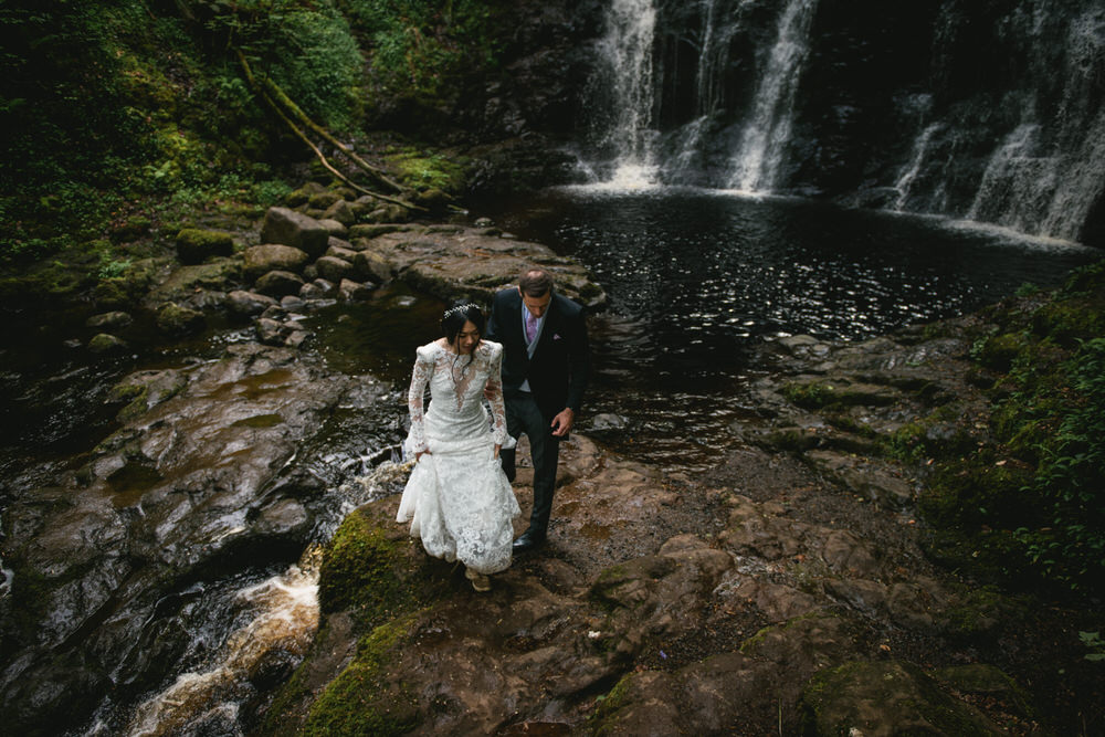 Couple holding hands on a hike surrounded by waterfalls during their Northern Ireland elopement.