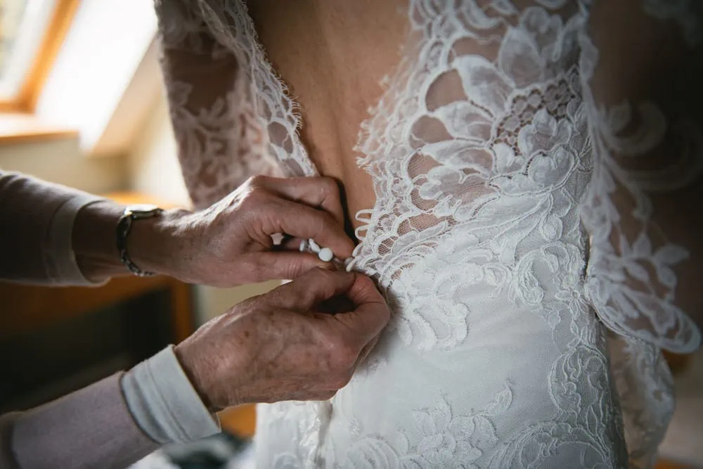 The bride's stunning lace wedding dress in harmony with the enchanting forest setting during her Northern Ireland elopement.