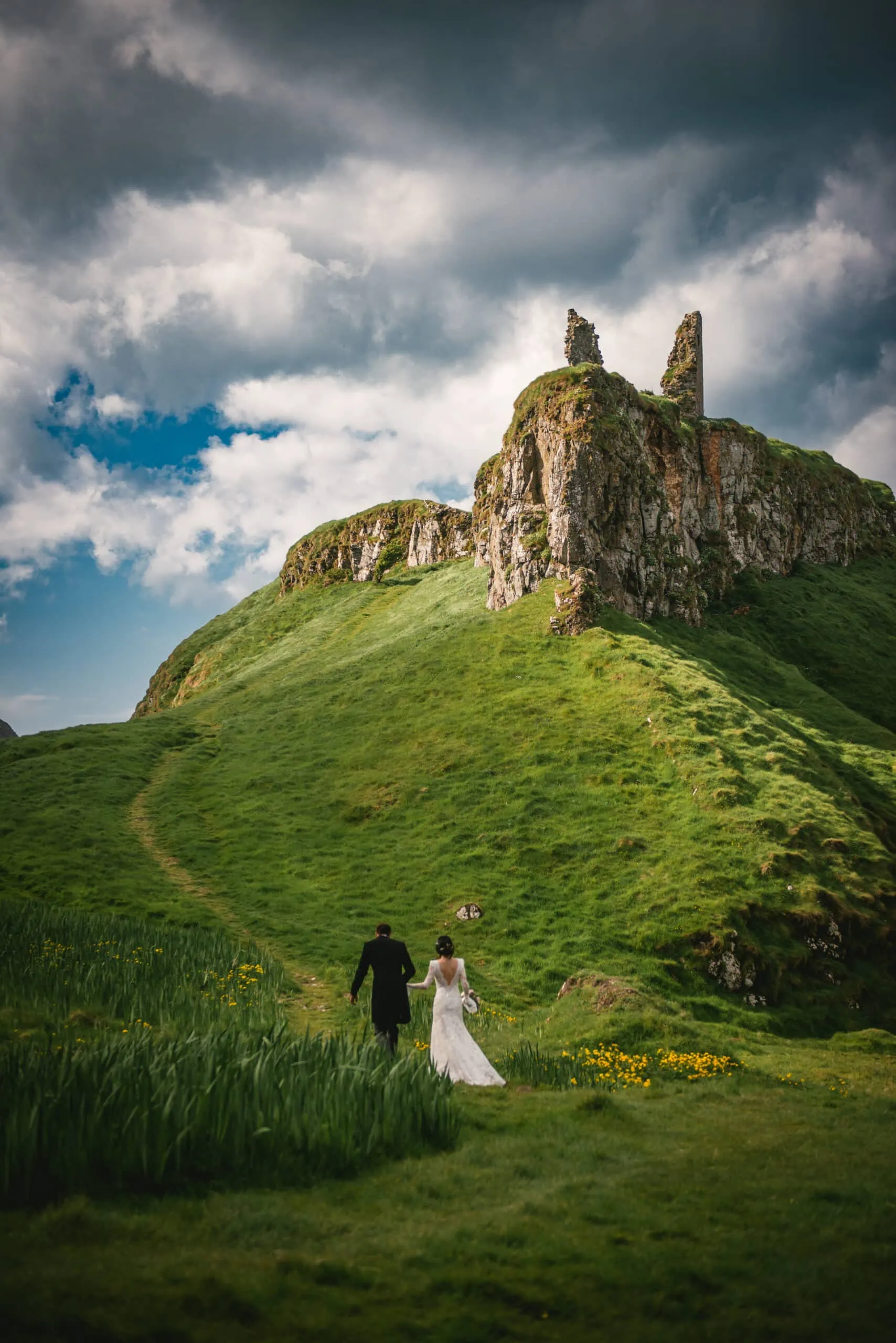The couple holding hands while exploring the ancient stone walls of the castle during their Northern Ireland elopement.