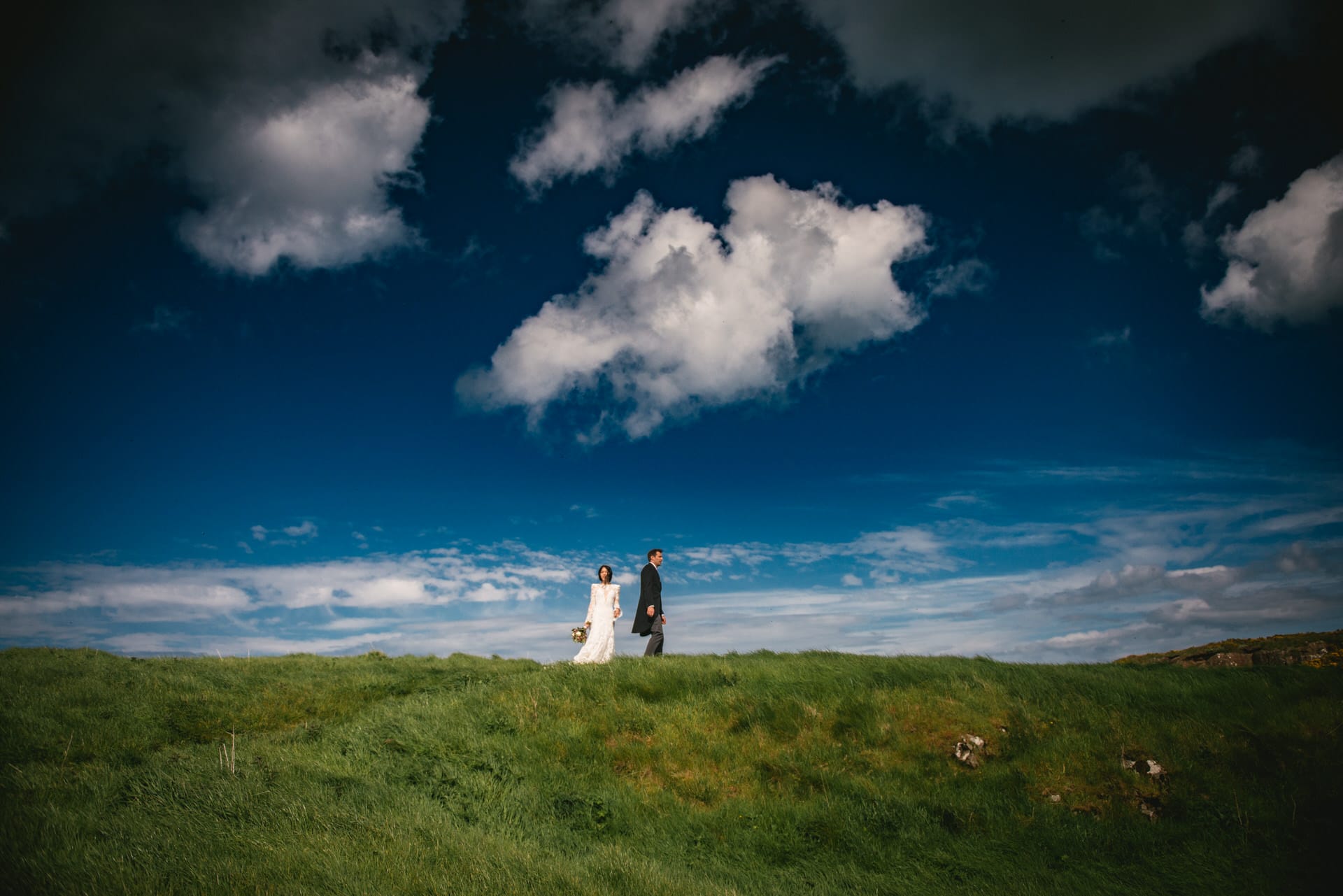 Candid shot of the couple walking along the rocky shoreline during their Northern Ireland elopement.