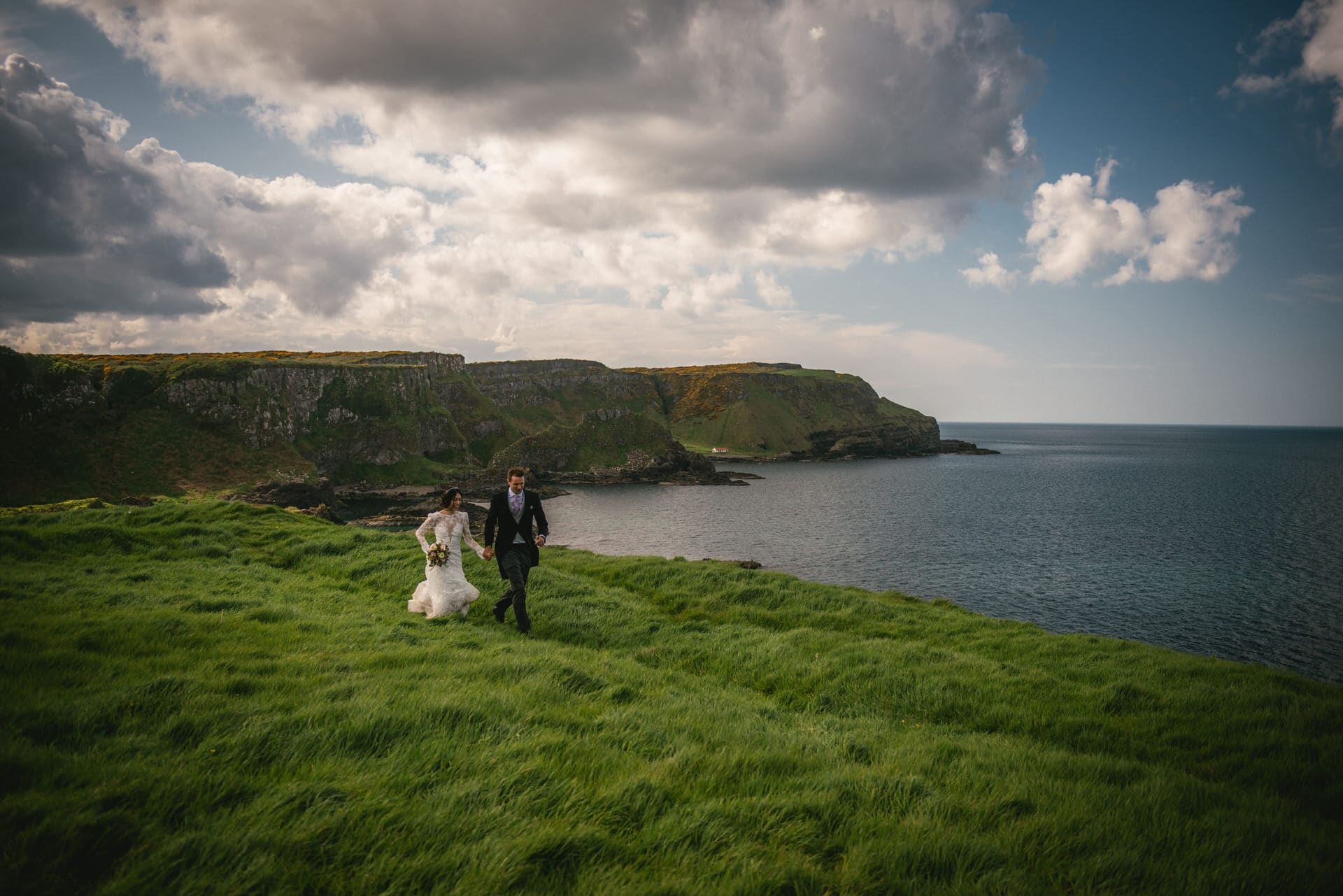 The couple embracing on a rocky cliff overlooking the sea during their Northern Ireland elopement.