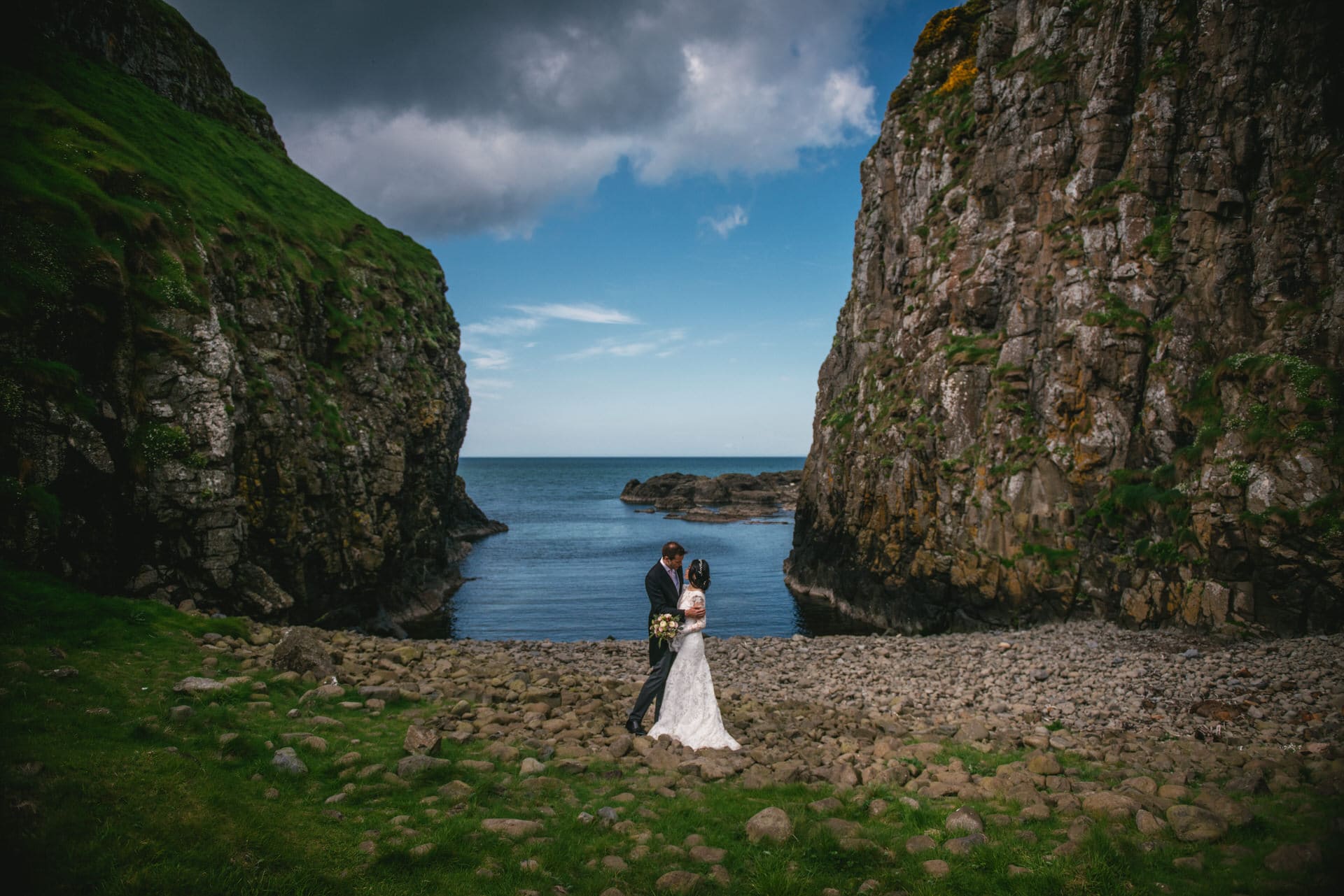 Candid shot of the couple stealing a kiss behind the castle ruins during their Northern Ireland elopement.