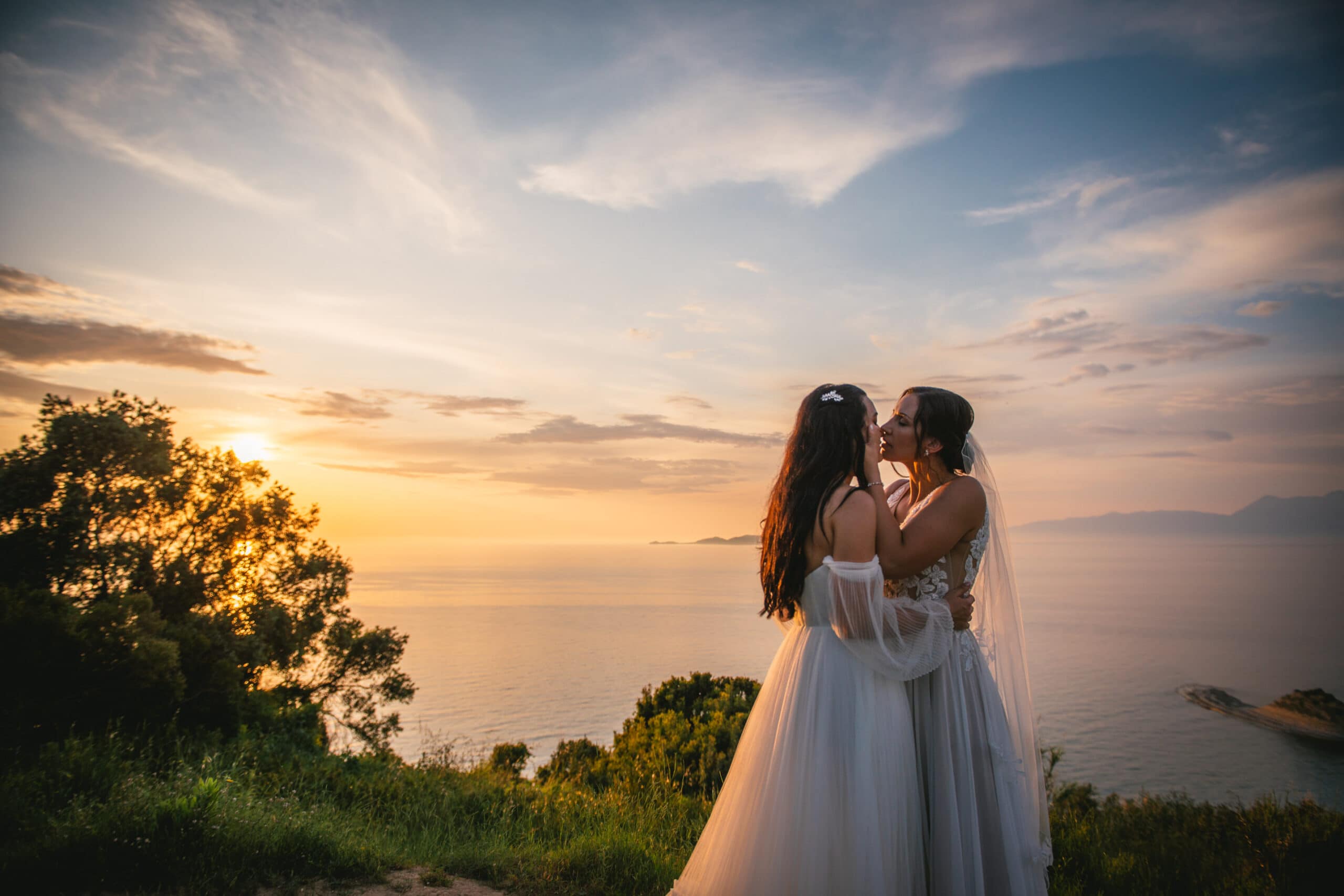 Brides snuggled close, sunset's warmth enveloping their Corfu elopement.