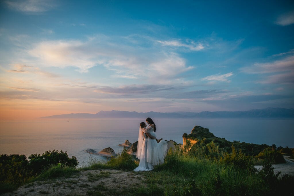 Brides striking a pose against the backdrop of a vibrant sunset, Corfu elopement joy.
