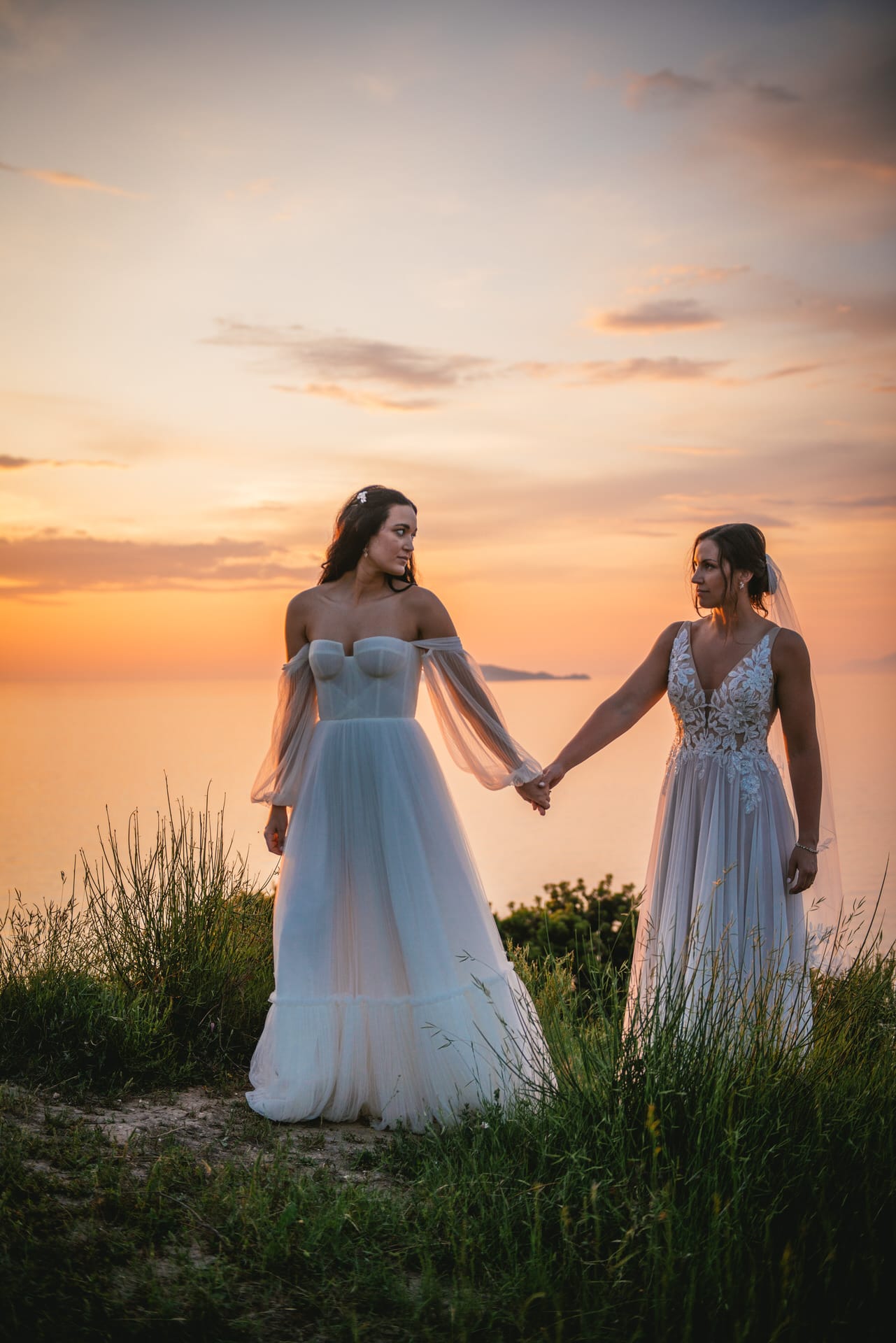 Brides walking hand in hand during sunset, a shared path in their Corfu elopement.