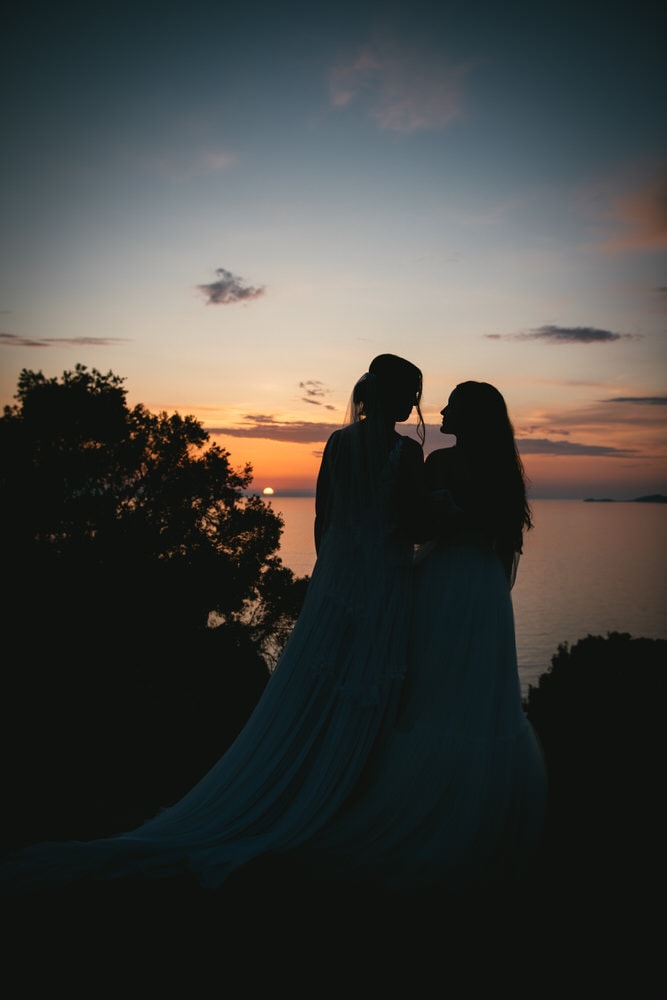 Brides silhouetted against a captivating Corfu sunset during their elopement.