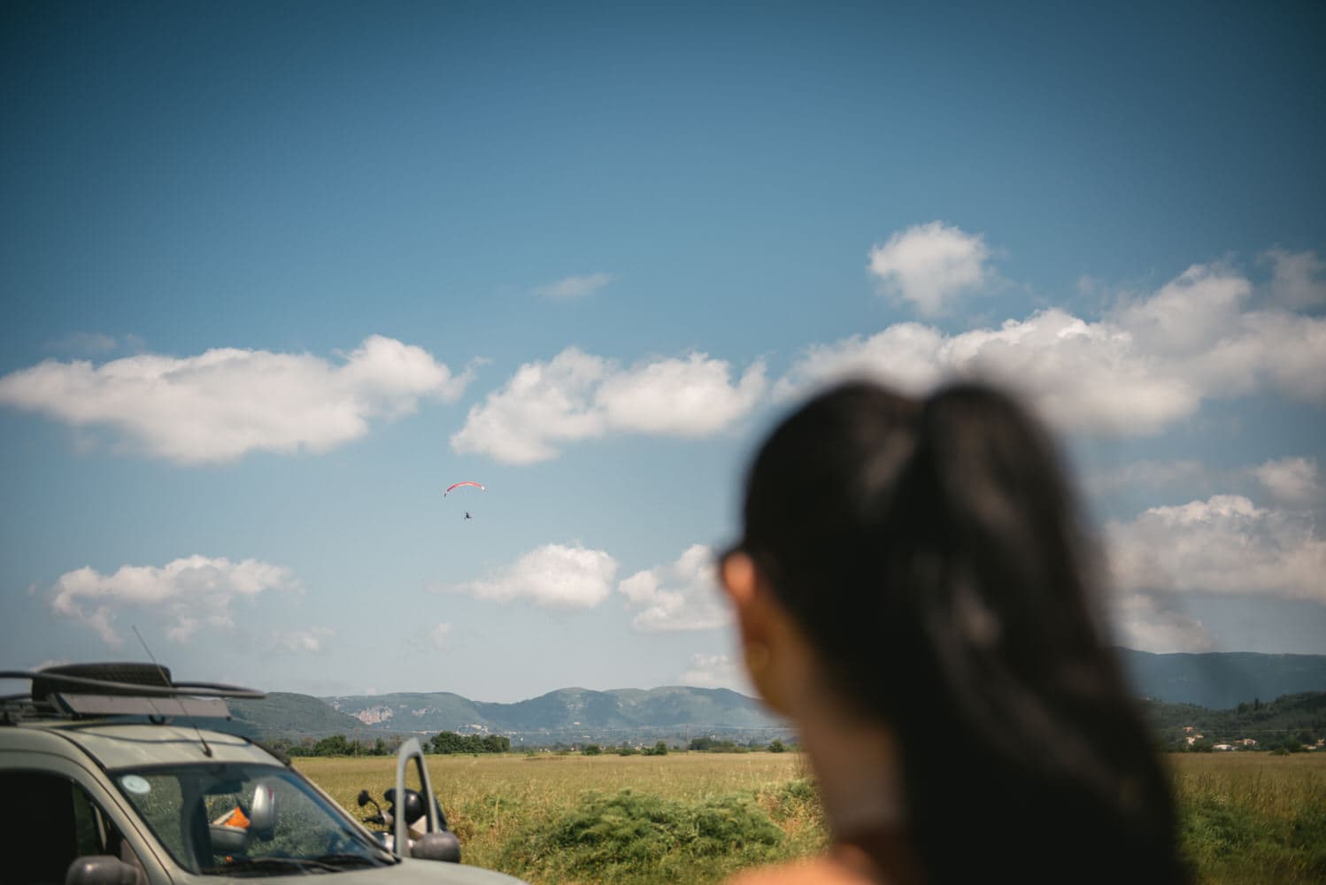 Bride's loving gaze towards her wife soaring in the paraglider during their Corfu elopement.
