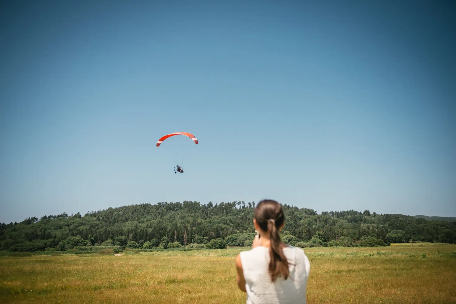 Bride's affectionate look as she watches her wife take off on a paraglider in Corfu.